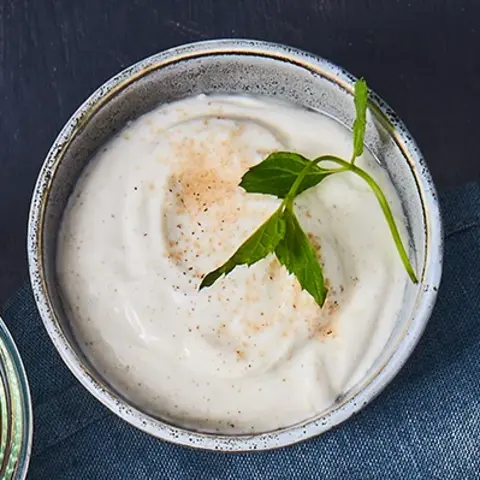 Knusprige Rösti serviert mit cremigem Vanillequark, gegrillten Nektarinenspalten, gerösteten Mandeln und frischen Minzblättern auf einem dunklen Teller. Daneben Schalen mit weiteren Zutaten wie Nektarinen und Vanillequark, dekoriert mit Vanilleschoten und einem blauen Stoffservietten.